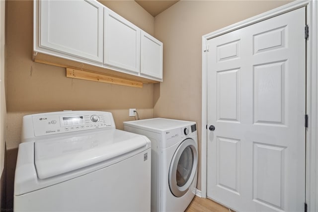 laundry area featuring cabinets, washer and dryer, and light hardwood / wood-style flooring