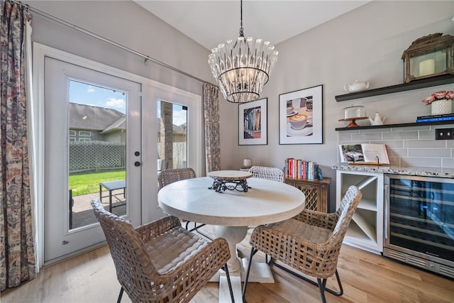 dining area featuring wine cooler, a chandelier, and light hardwood / wood-style floors