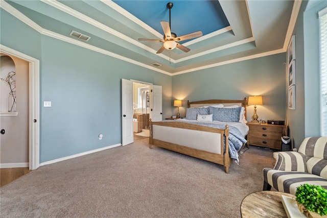 bedroom with carpet flooring, ensuite bathroom, ornamental molding, ceiling fan, and a raised ceiling