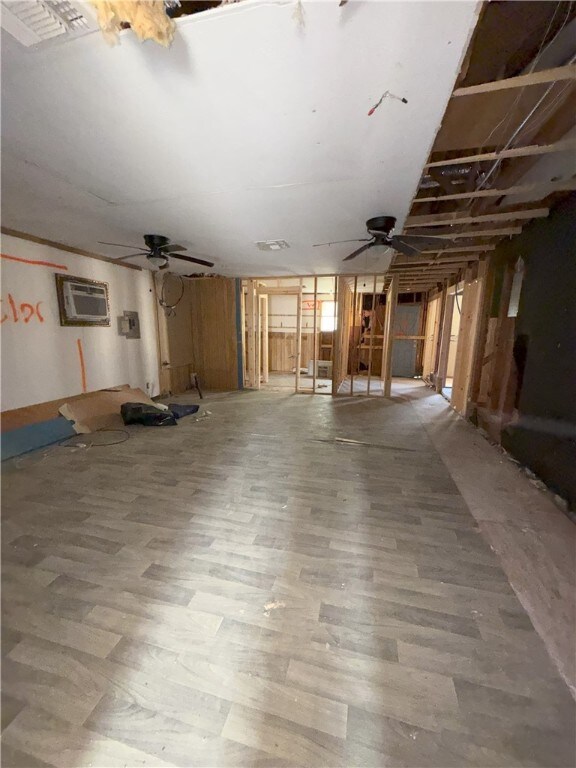 basement featuring a wall mounted AC, hardwood / wood-style flooring, and ceiling fan