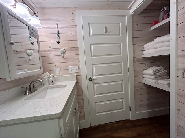 bathroom featuring vanity, wooden walls, and hardwood / wood-style flooring