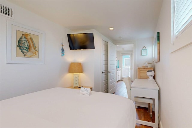 bedroom with ensuite bathroom and hardwood / wood-style flooring