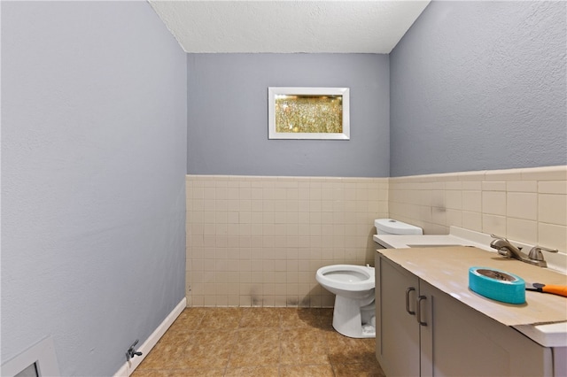 bathroom with tile walls, tile patterned floors, vanity, a textured ceiling, and toilet