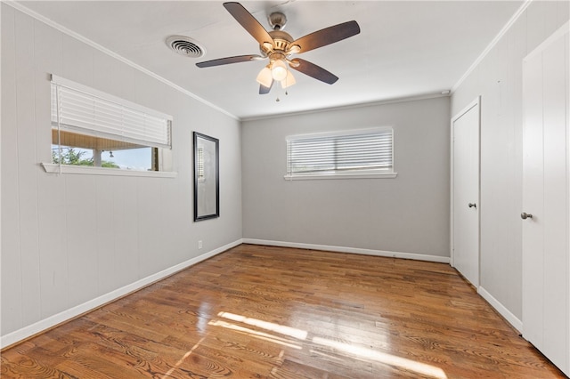 empty room featuring ceiling fan, hardwood / wood-style floors, and ornamental molding