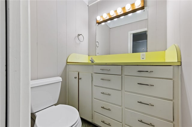 bathroom featuring vanity, toilet, and wooden walls