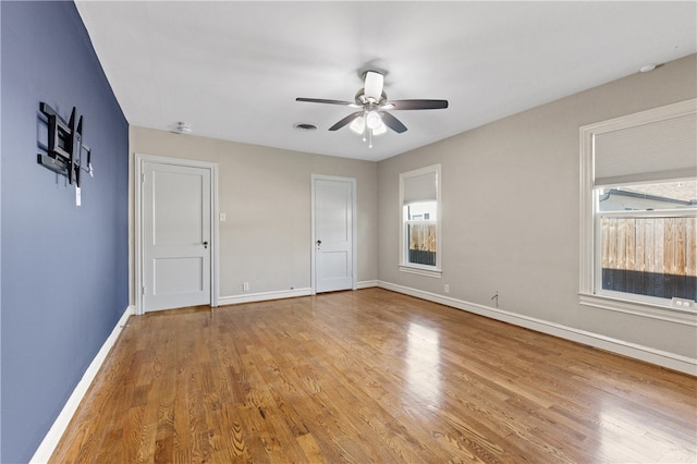 unfurnished bedroom featuring ceiling fan, multiple windows, and light hardwood / wood-style flooring