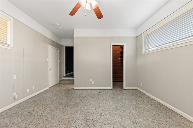 unfurnished bedroom featuring ceiling fan, multiple windows, a closet, and a walk in closet