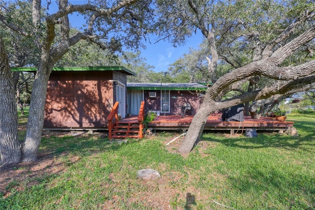 rear view of house featuring a lawn and a deck