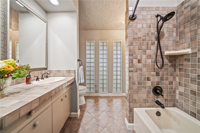 full bathroom with tile patterned floors, tiled shower / bath, vanity, and toilet