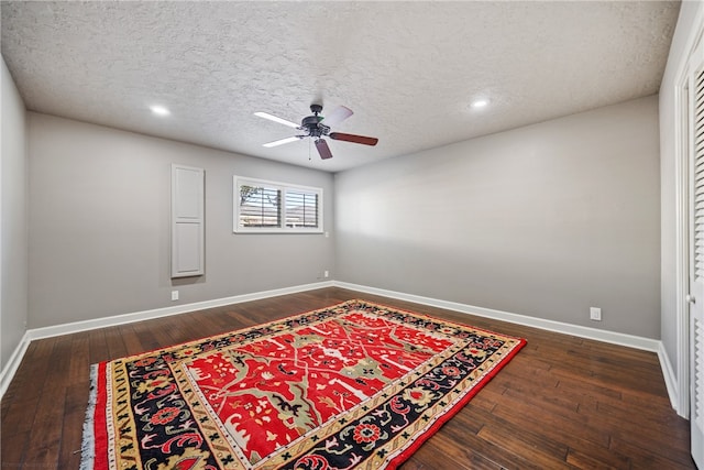 unfurnished room with ceiling fan, dark hardwood / wood-style flooring, and a textured ceiling