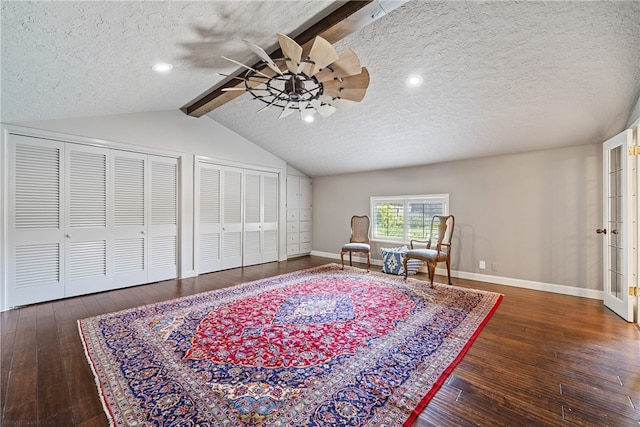 living area featuring vaulted ceiling with beams, ceiling fan, dark hardwood / wood-style flooring, and a textured ceiling