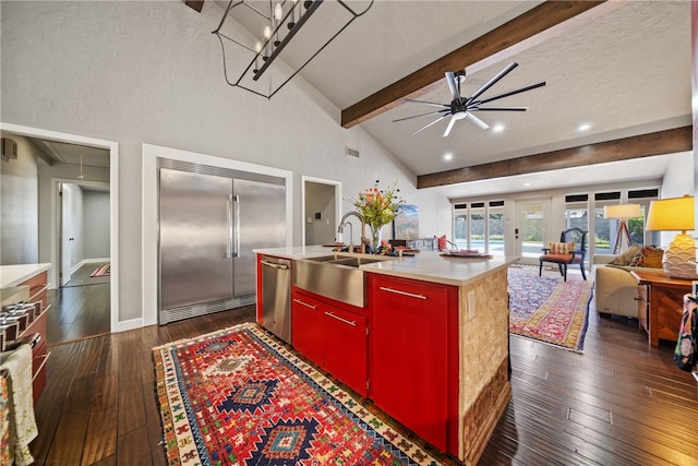 kitchen with ceiling fan, sink, dark wood-type flooring, a kitchen island with sink, and appliances with stainless steel finishes