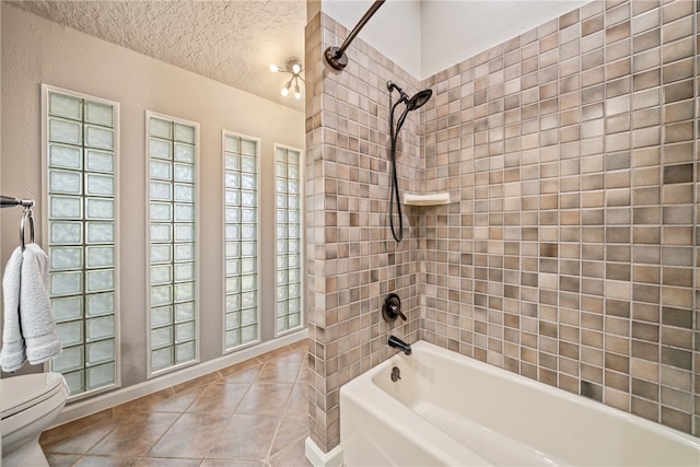 bathroom featuring a textured ceiling, toilet, and tiled shower / bath