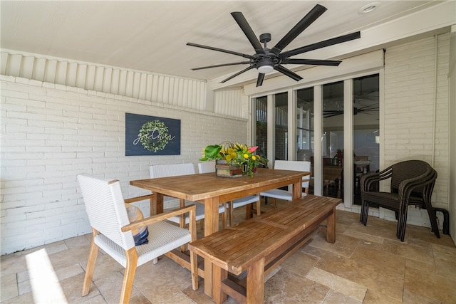 dining room with ceiling fan and brick wall