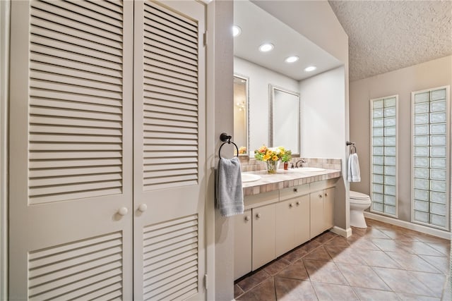 bathroom with tile patterned flooring, vanity, a textured ceiling, and toilet