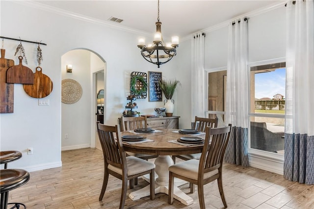 dining area featuring arched walkways, visible vents, baseboards, light wood-type flooring, and crown molding