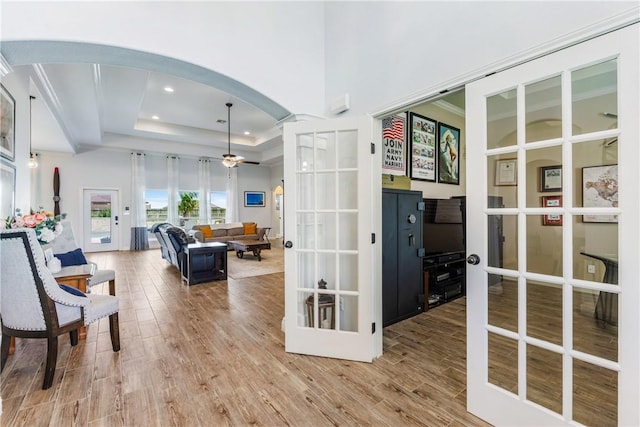 interior space featuring arched walkways, recessed lighting, wood finished floors, french doors, and a raised ceiling