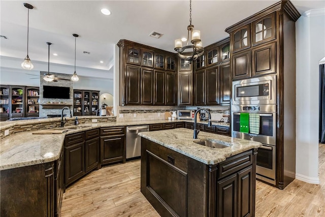 kitchen featuring light wood-style floors, appliances with stainless steel finishes, pendant lighting, and a sink