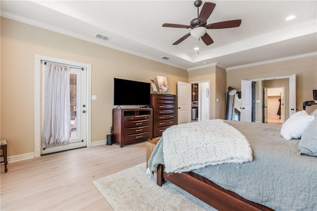 bedroom with light wood-type flooring, crown molding, visible vents, and a tray ceiling