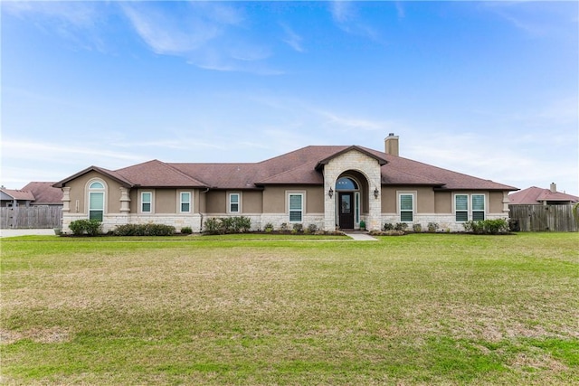 view of front of property featuring a front yard, fence, a chimney, and stucco siding