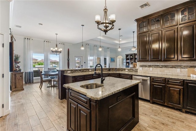 kitchen featuring a center island with sink, visible vents, decorative backsplash, dishwasher, and a sink