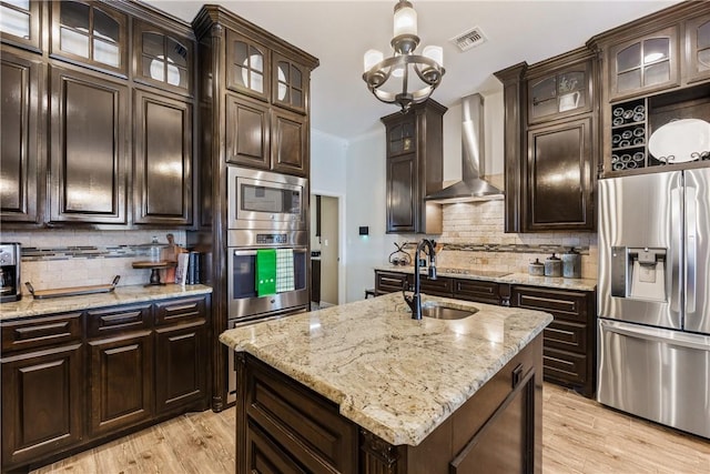 kitchen with crown molding, stainless steel appliances, visible vents, a sink, and wall chimney exhaust hood