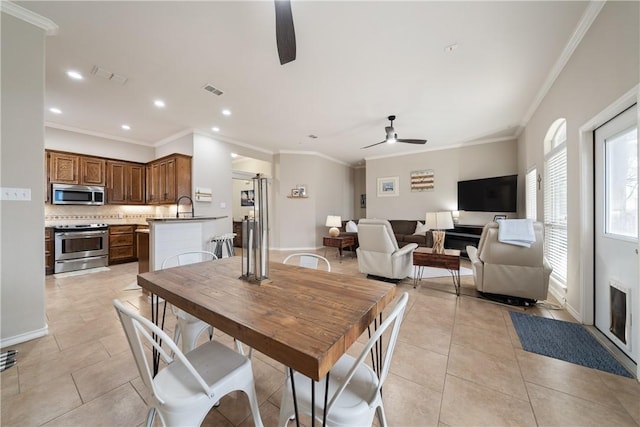 tiled dining space featuring ceiling fan, ornamental molding, and sink