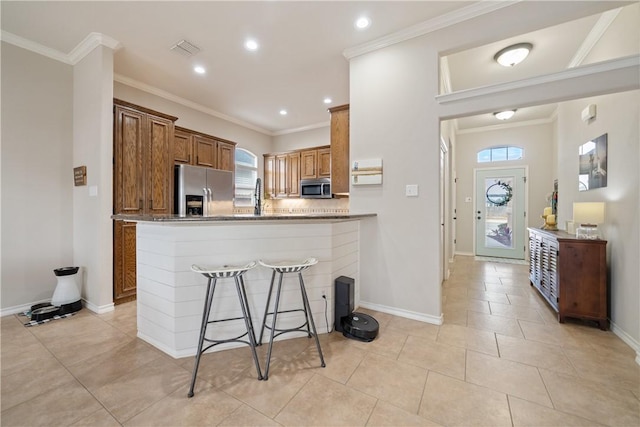 kitchen with light tile patterned floors, crown molding, a kitchen breakfast bar, stainless steel appliances, and kitchen peninsula