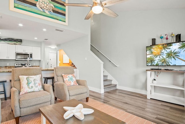 living area featuring light wood finished floors, baseboards, visible vents, stairs, and recessed lighting