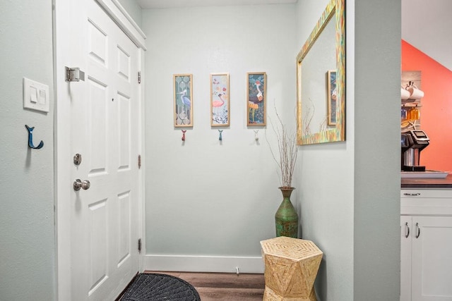 doorway to outside featuring baseboards and wood finished floors