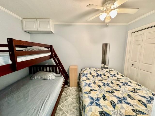 bedroom with ornamental molding, ceiling fan, and a closet