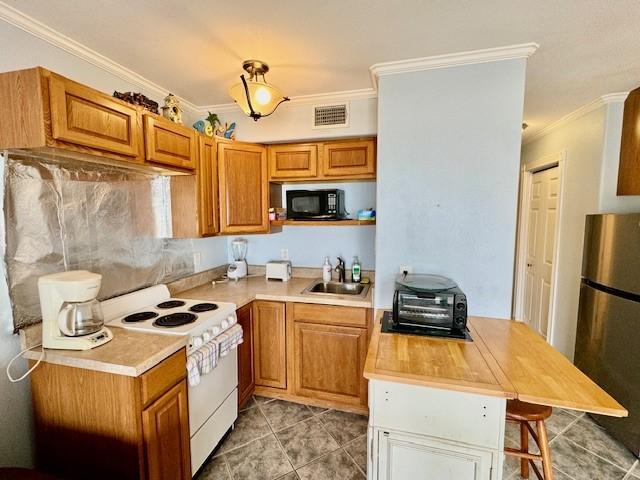 kitchen featuring crown molding, a breakfast bar, stainless steel refrigerator, and white range with electric cooktop