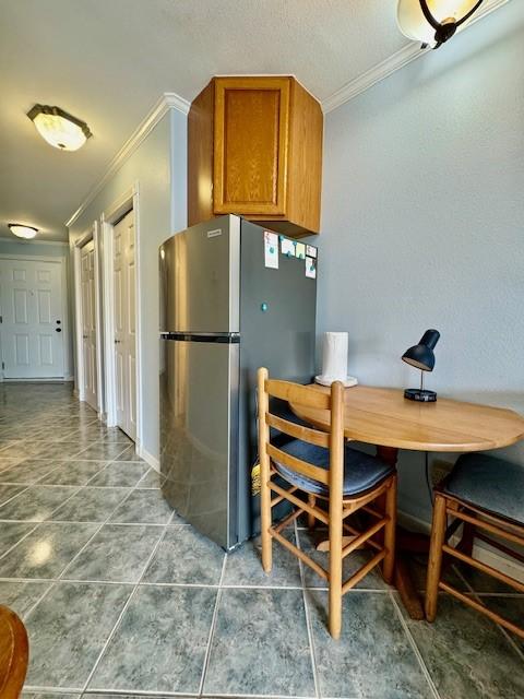 kitchen featuring stainless steel refrigerator, crown molding, and tile patterned flooring