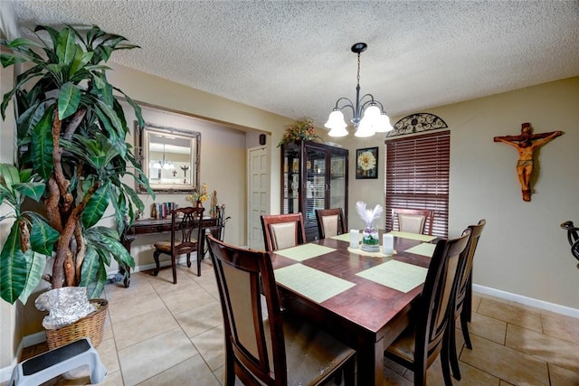 dining area with a notable chandelier, a textured ceiling, baseboards, and light tile patterned floors