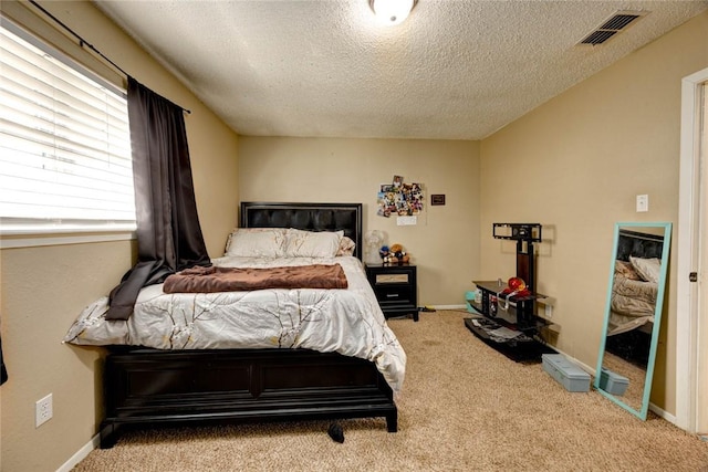 carpeted bedroom featuring baseboards, visible vents, and a textured ceiling