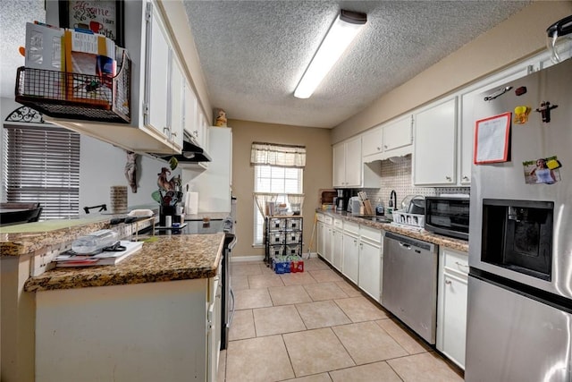 kitchen with light tile patterned floors, a sink, white cabinets, appliances with stainless steel finishes, and tasteful backsplash