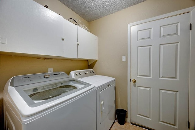 laundry room featuring a textured ceiling, washing machine and dryer, and cabinet space