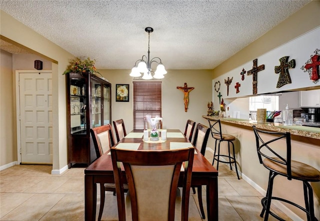 dining room featuring a notable chandelier, a textured ceiling, baseboards, and light tile patterned floors