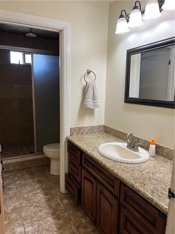 bathroom with tile patterned floors, vanity, toilet, and a tile shower