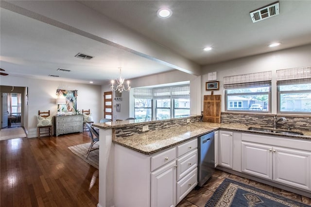 kitchen featuring a peninsula, visible vents, stainless steel dishwasher, and a sink