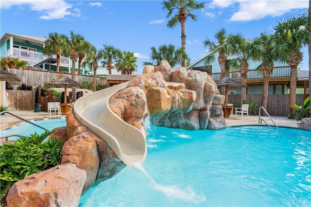 view of pool with a patio, a water slide, a gazebo, and pool water feature