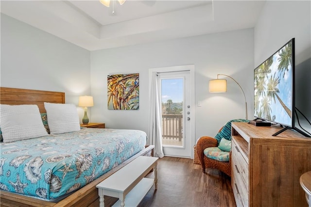 bedroom with ceiling fan, access to exterior, dark hardwood / wood-style flooring, and a tray ceiling