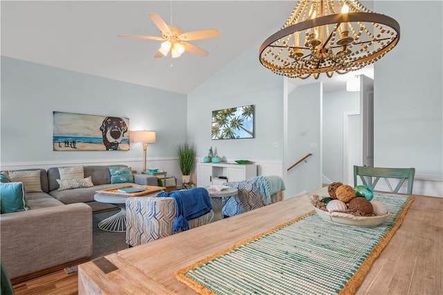 dining area featuring high vaulted ceiling, wood-type flooring, and ceiling fan with notable chandelier