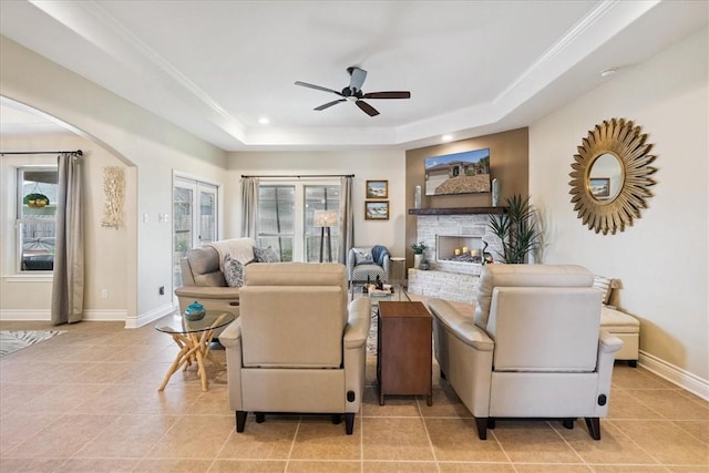15825 Cozumel Dr, Corpus Christi, TX 78418 - living area with a raised ceiling, a ceiling fan, light tile patterned floors, a warm lit fireplace, and arched walkways