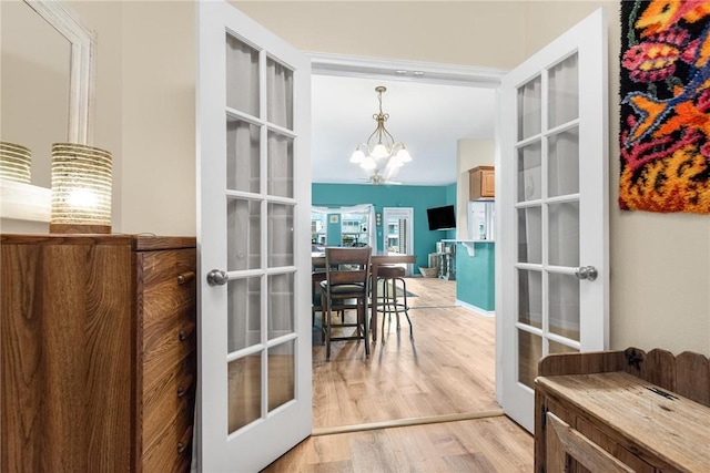 entryway featuring french doors, light hardwood / wood-style flooring, and a notable chandelier