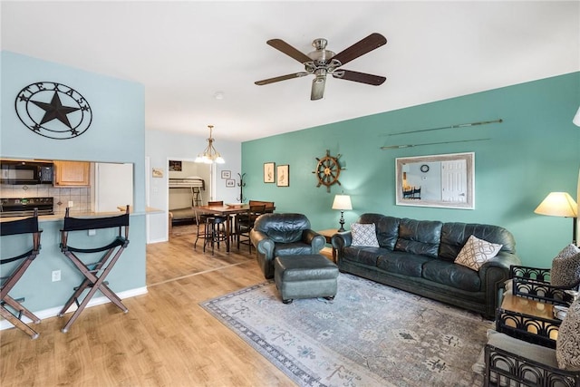 living room with ceiling fan with notable chandelier and light hardwood / wood-style floors