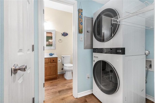 laundry room featuring stacked washer / drying machine and hardwood / wood-style floors