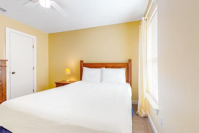 bedroom featuring multiple windows, light colored carpet, and ceiling fan