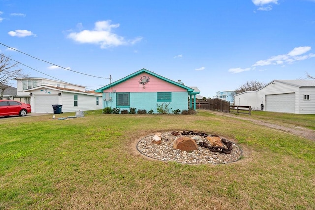 view of front facade featuring a garage, an outdoor fire pit, fence, and a front yard