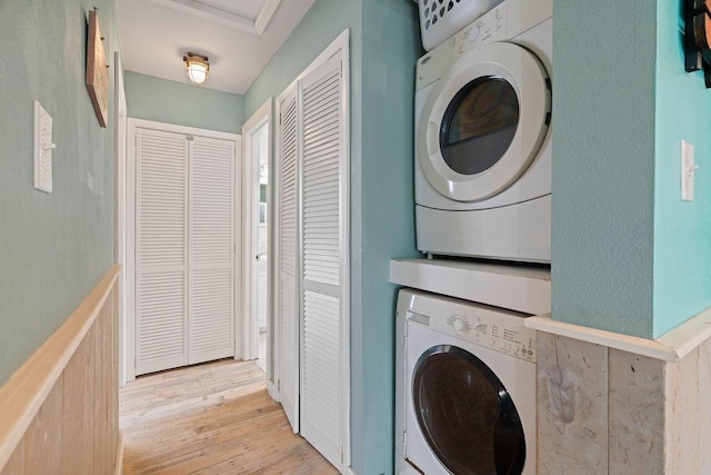 washroom with light wood-style floors, stacked washer / dryer, and laundry area